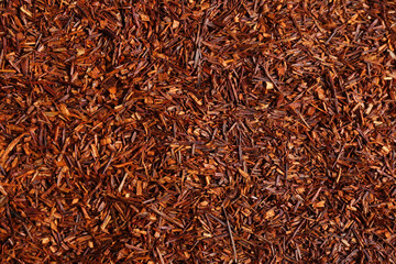 Heap of dry rooibos tea leaves as background, top view