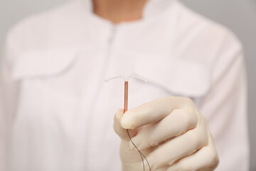 Doctor holding T-shaped intrauterine birth control device, closeup