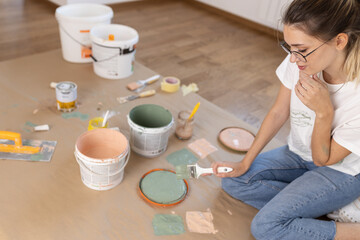 Young female preparing and mixiig paint to decorate walls in her new home.	
