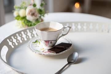 Stylish cup of espresso black coffee with black chocolate on beautiful white tray