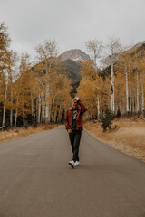 Man walking/modeling in the road in the middle of the mountains, with fall foliage
