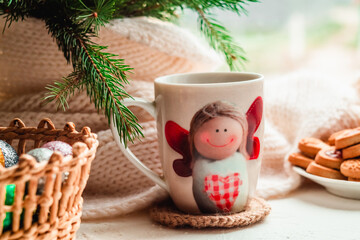 A cup of hot black tea with an angel on the windowsill. Christmas fragrant tea.