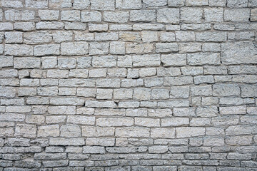 old brick wall made of limestone blocks of different sizes as the background