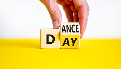 International Dance Day symbol. Businessman turns a wooden cube with words 'dance day'. Beautiful yellow table, white background, copy space. International Dance Day concept.