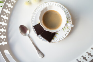 Stylish cup of espresso black coffee with black chocolate on beautiful white tray