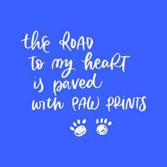 THE ROAD TO MY HEART IS PAVED WITH PAW PRINTS. MOTIVATIONAL HAND LETTERING TEXT PHRASE ABOUT DOGS.