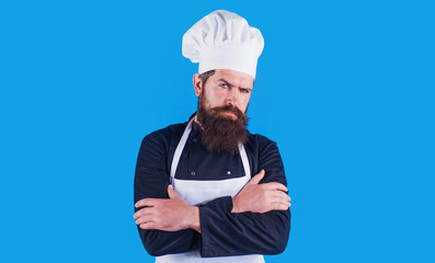 Serious bearded chef in uniform and apron with arms crossed. Cooking, profession and people concept.