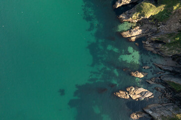 Fototapeta na wymiar Aerial image of a green sea and rocky coastline in Cornwall, UK