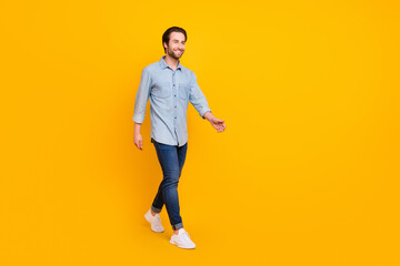 Fototapeta na wymiar Full length profile side photo of young cheerful man happy positive smile go walk look empty space isolated over yellow color background