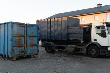 Truck with a loaded container next to an empty logistics container.