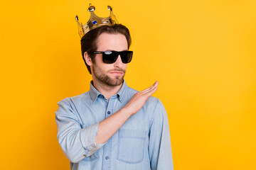 Photo of young narcissistic man rich arrogant serious prince crown look empty space isolated over yellow color background