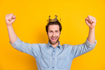 Fototapeta premium Photo of young excited man happy positive smile rejoice victory wear crown wealthy prince isolated over yellow color background