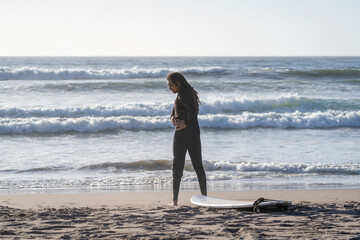 latin man stretching on the beach before surfing the waves in La Serena