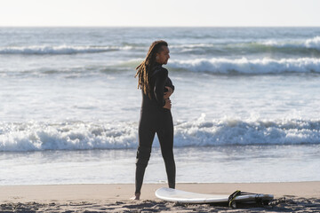 latin man stretching on the beach before surfing the waves in La Serena