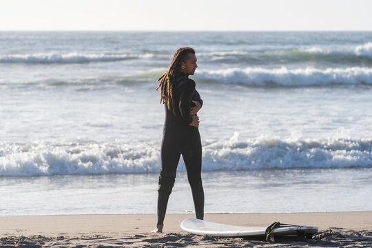 latin man stretching on the beach before surfing the waves in La Serena