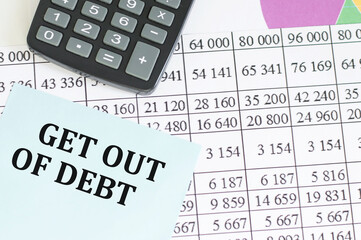 card with text get out of debt and calculator on office desk