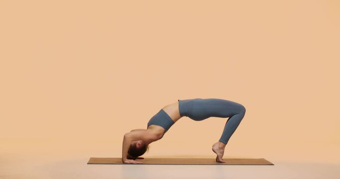 Fit young girl practicing yoga perform Wheel Pose in studio. Perfect body, woman health and mindful healthy lifestyle