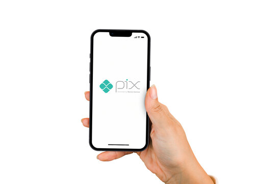 Female hand holding a smartphone iPhone 13 Pro with Pix app on the screen. White background. Rio de Janeiro, RJ, Brazil. November 2021