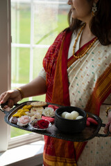 Woman is sari holding a tray of Indian sweet 