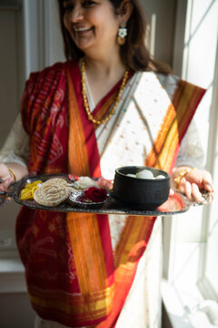 Woman is sari holding a tray of Indian sweet 