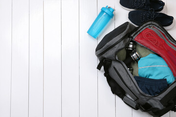 Gym bag and sports equipment on white wooden background, flat lay. Space for text