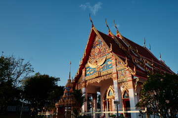 Naklejka premium Highly decorated red-golden roof of Wat temple depicting buddha and disciples.