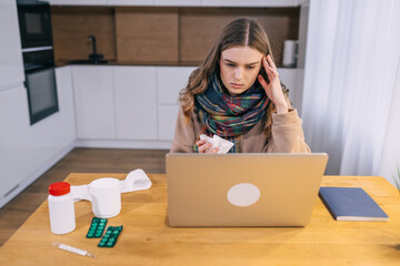 young woman sitting at table at home working with laptop compute