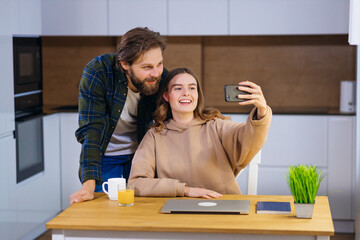Fototapeta premium A young couple, at home in the kitchen, contacted their parents