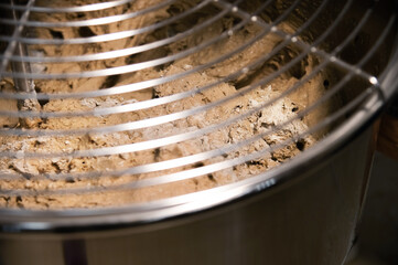 Close-up of dough for the production of artisan bread is kneaded in a production dough mixer