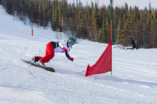athlete girl with a hard snowboard for slalom in a ski resort enters the turn, Murmansk region, Russia.