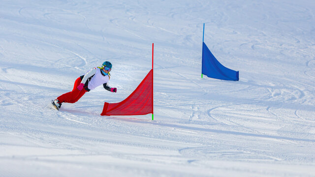 athlete girl with a hard snowboard for slalom in a ski resort enters the turn, Murmansk region, Russia.