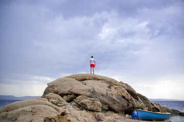 Sylwetka młody mężczyzna stojący na skale na tle pięknego nieba - obrazy, fototapety, plakaty