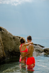 Młoda kobieta i mężczyzna przytulona para  stojąca w błękitnej wodzie na tle skał