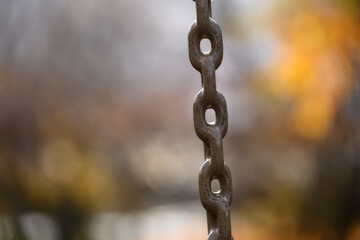 closeup of the chain of a children's swing against a yellow and brown background