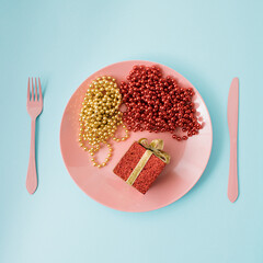 Creative flat lay with pink plate with cutlery, spoon kinfe and fork , abstract Christmas decoration on colored background pink and light blue. Retro aesthetic style. New Year party props 