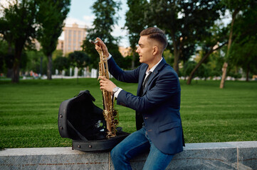 Male saxophonist takes the saxophone from the case