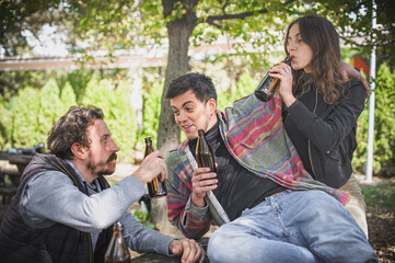 Cheers. Smiling cheerful young friends drinks beer from bottle