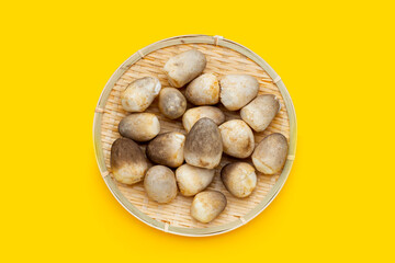 Straw mushroom in round bamboo basket on yellow background.