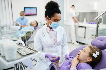 Small girl complains about toothache during appointment at dentist's office.