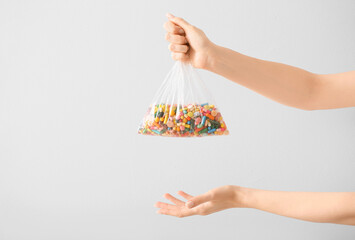 Female hands with pills in plastic bag on light background