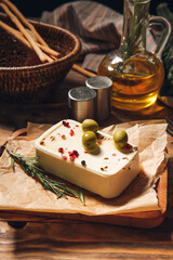 Board with feta cheese, spices and olives on wooden background