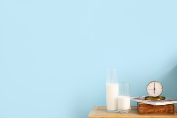Alarm clock, magazine and candles on table near color wall