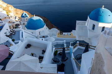 Fototapeta premium View from viewpoint of Oia village with blue domes of greek orthodox Christian churches and traditional whitewashed greek architecture. Santorini, Greece