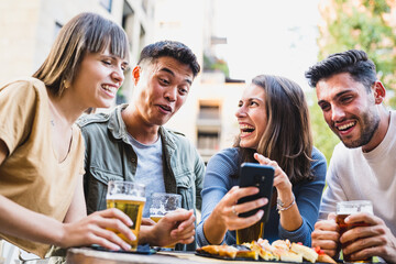 young people having fun at brewery, a laughing woman joking with friends, looking at smartphone, young asian man making a funny face - millennials lifestyle, happiness and carefree concept