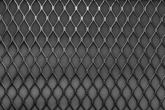Metal grid with geometric pattern of rhombi, background. Black metallic modern background
