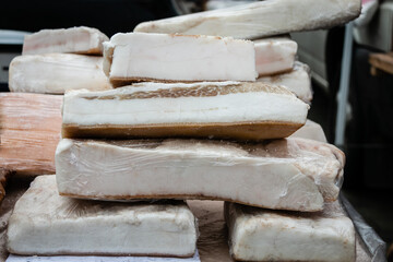 Large chunks of fresh salted bacon on the counter in the village market. Close-up. Natural food. Natural product from an organic farm, produced using traditional methods.