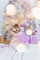 Fototapeta na wymiar Cute little baby girl opening gift box with decorating christmas tree on background