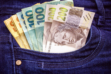 Brazilian money bills, 100, 200 and 50 reais bills in pants pockets, prize or jackpot concept