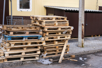 a stack of old wooden pallets in the yard , used pallets stacked on the sidewalk