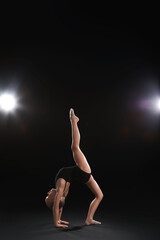 Little girl doing gymnastics on dark background